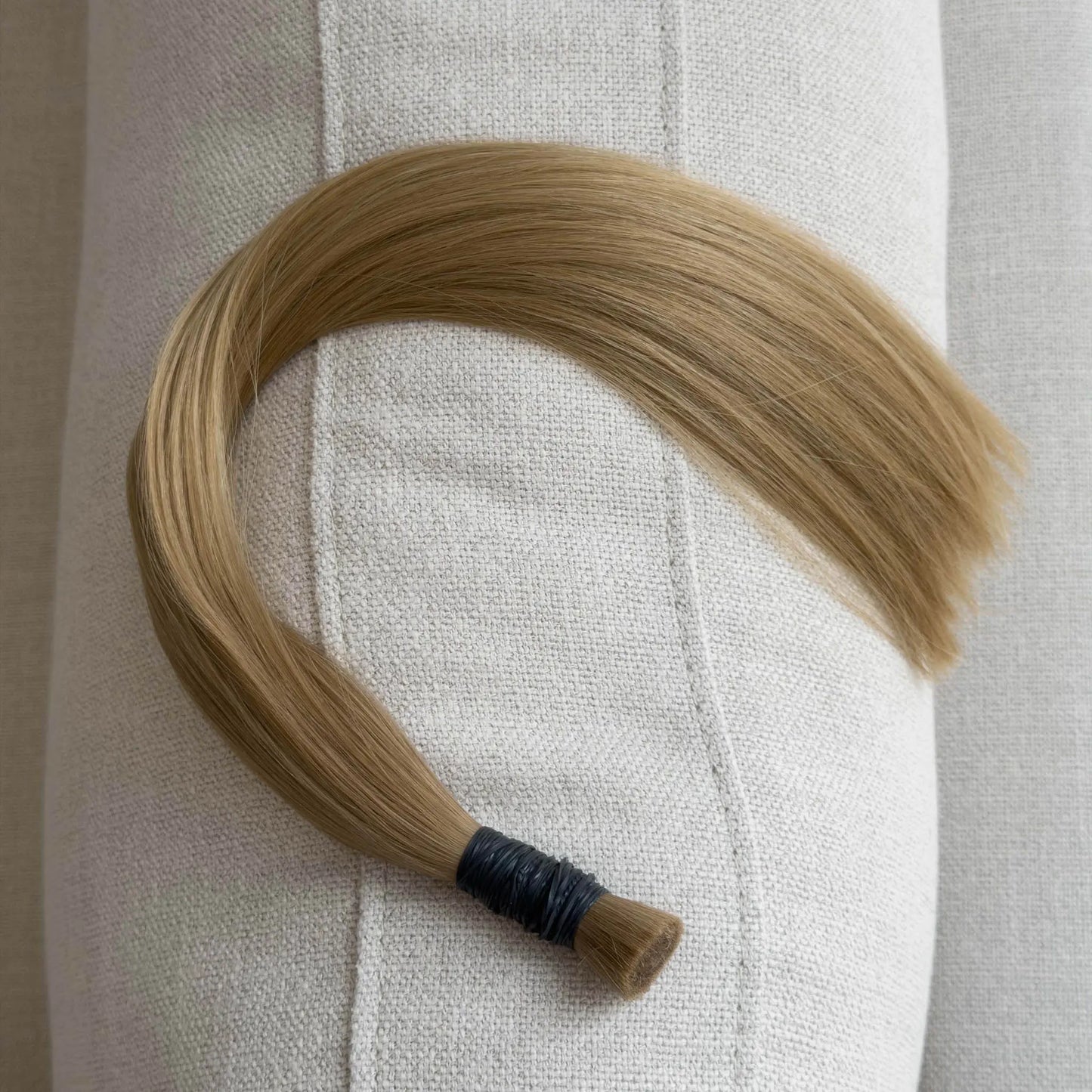 Blonde hair extension on a white fabric background