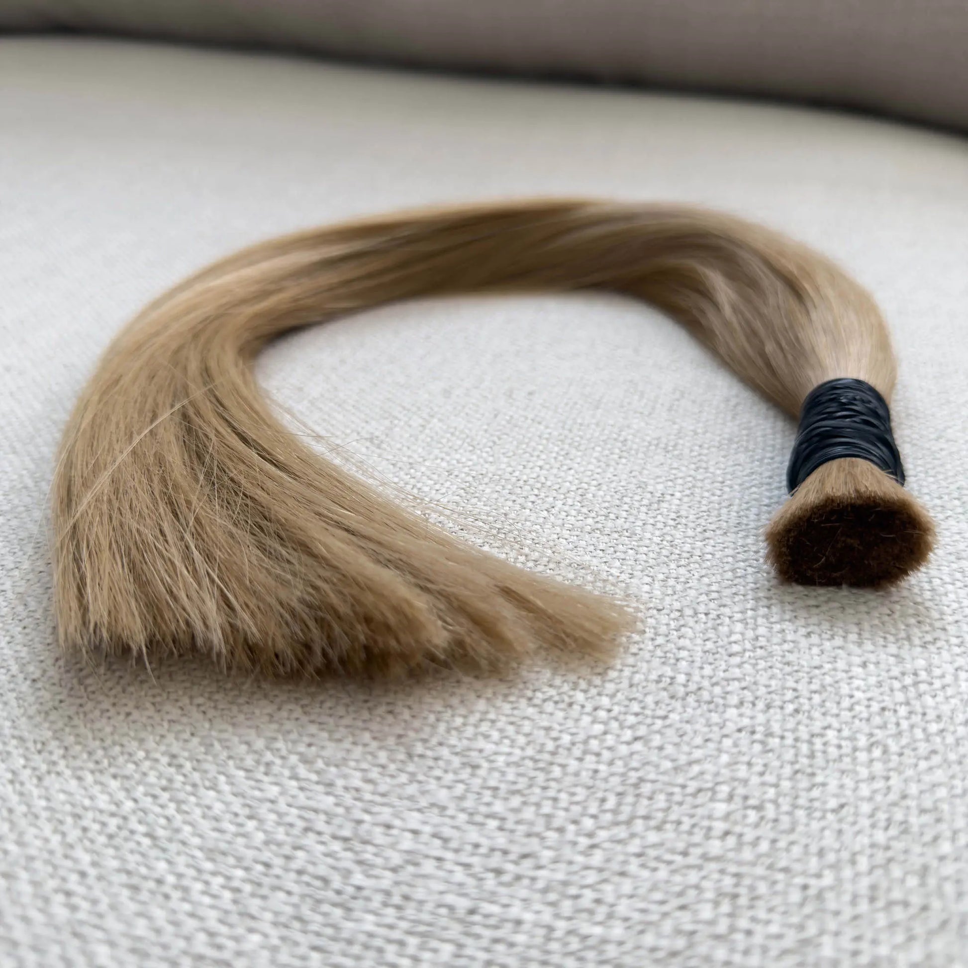 Blonde, colour number 10 hair extension on a textured surface