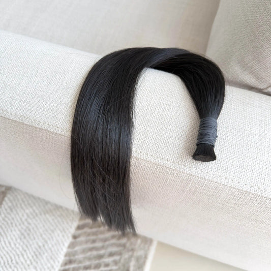 Black, colour 1b hair extension on a white surface