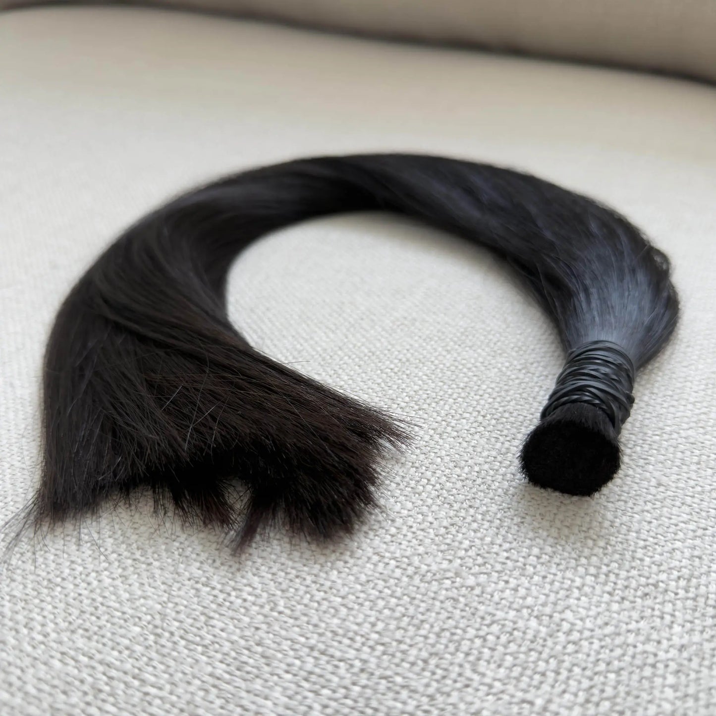 Black, colour 1b hair extensions on a textured surface