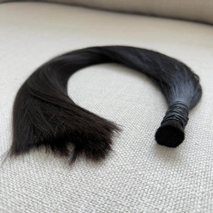 Black, colour 1b hair extensions on a textured surface