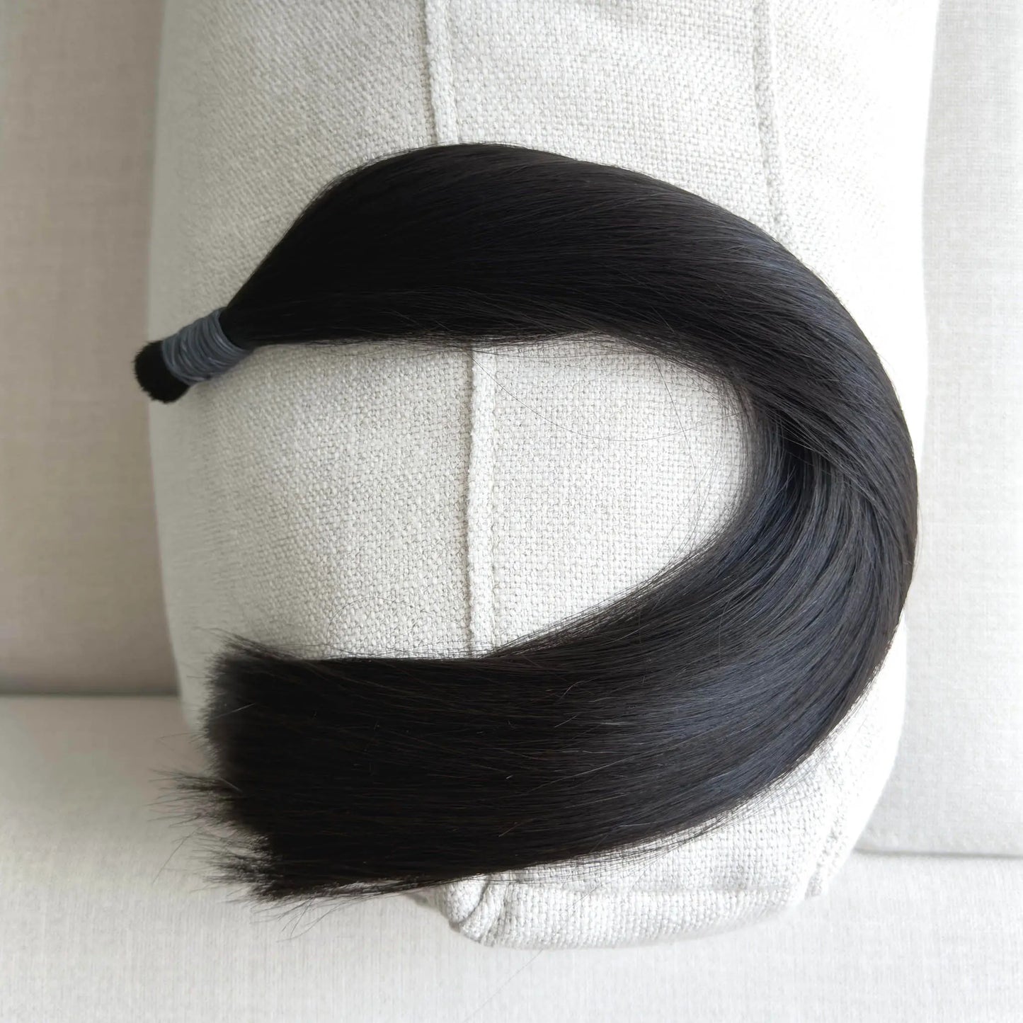 Black, colour 1b hair extension on a mannequin head against a neutral background