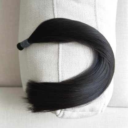 Black, colour 1b hair extension on a mannequin head against a neutral background