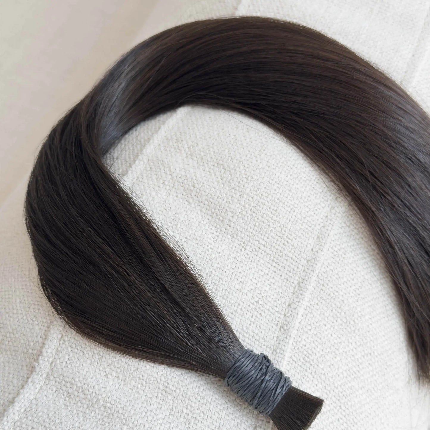 Single hair extension on a textured beige surface