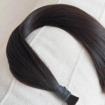 Single hair extension on a textured beige surface
