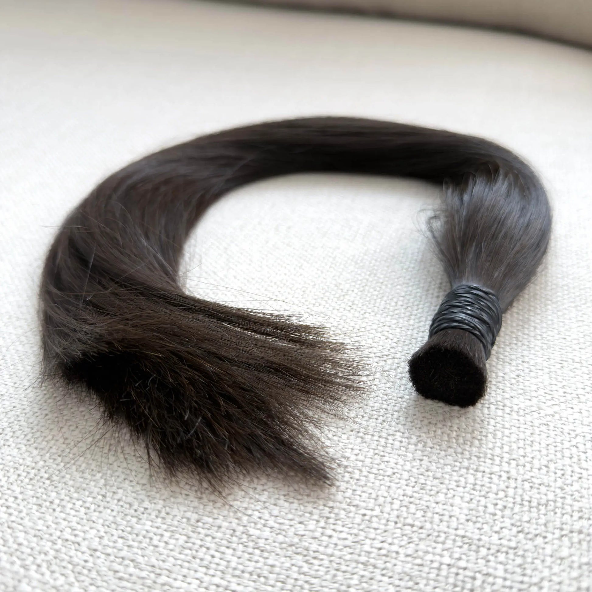 Single hair strand on a textured beige surface