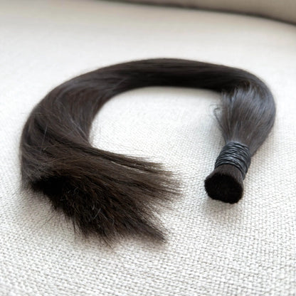 Single hair strand on a textured beige surface