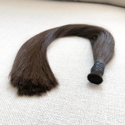 Brown, colour 4 hair extension on a textured white surface