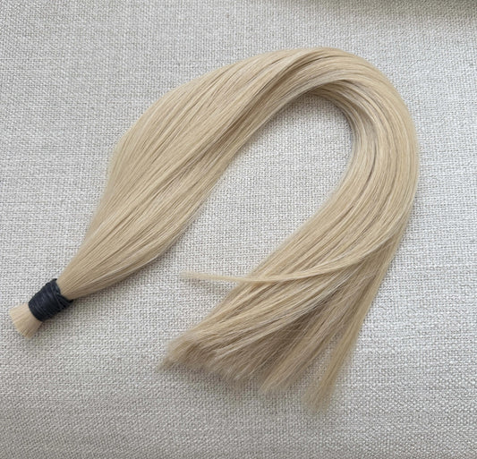 Blonde number 60 hair extensions on a textured beige background