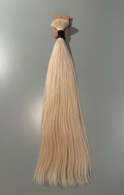 A bundle of long, straight blonde Slavic hair extensions with a black band and a small cardboard header, displayed against a plain gray background.