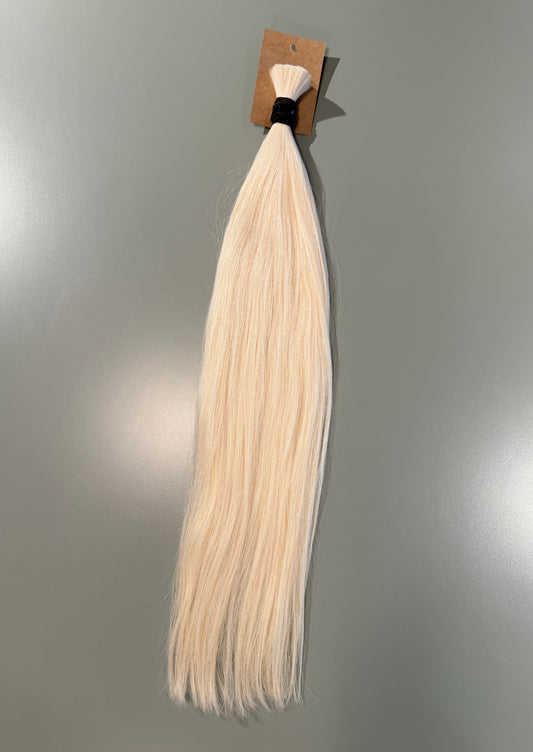 A single bundle of long, straight blonde slavic hair extensions tied to a small cardboard card with a black elastic band, shown against a plain gray background.